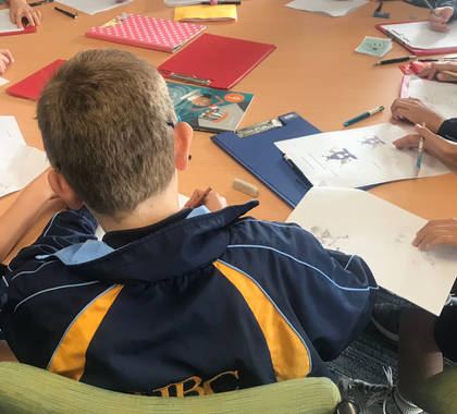 A student drawing at a table covered in sketches